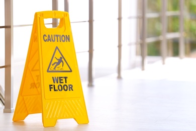 Photo of Safety sign with phrase Caution wet floor, indoors. Cleaning service