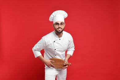 Professional chef with serving board having fun on red background