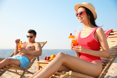 Photo of Couple with drinks resting on sunny beach at resort