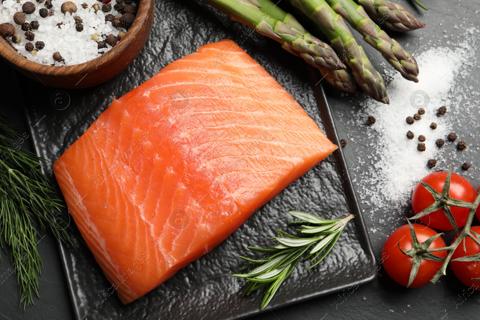 Photo of Fresh raw salmon and ingredients for marinade on black table, flat lay