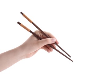 Photo of Woman holding pair of wooden chopsticks on white background, closeup