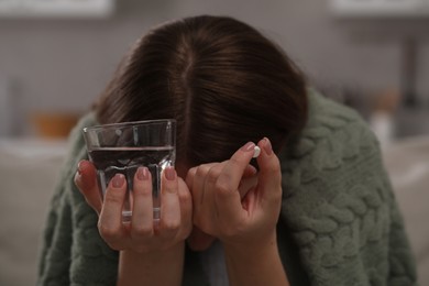 Photo of Depressed woman with antidepressant pill and glass of water indoors