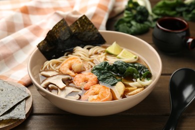 Delicious ramen with shrimps and mushrooms in bowl served on wooden table, closeup. Noodle soup