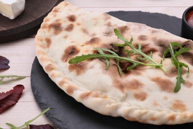 Photo of Delicious calzone on light wooden table, closeup