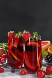Delicious refreshing sangria and ingredients on light grey table, space for text