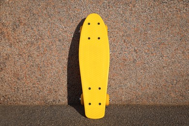 Photo of Stylish yellow skate board near wall outdoors
