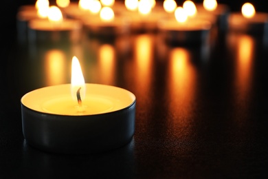 Wax candle burning on table in darkness, closeup