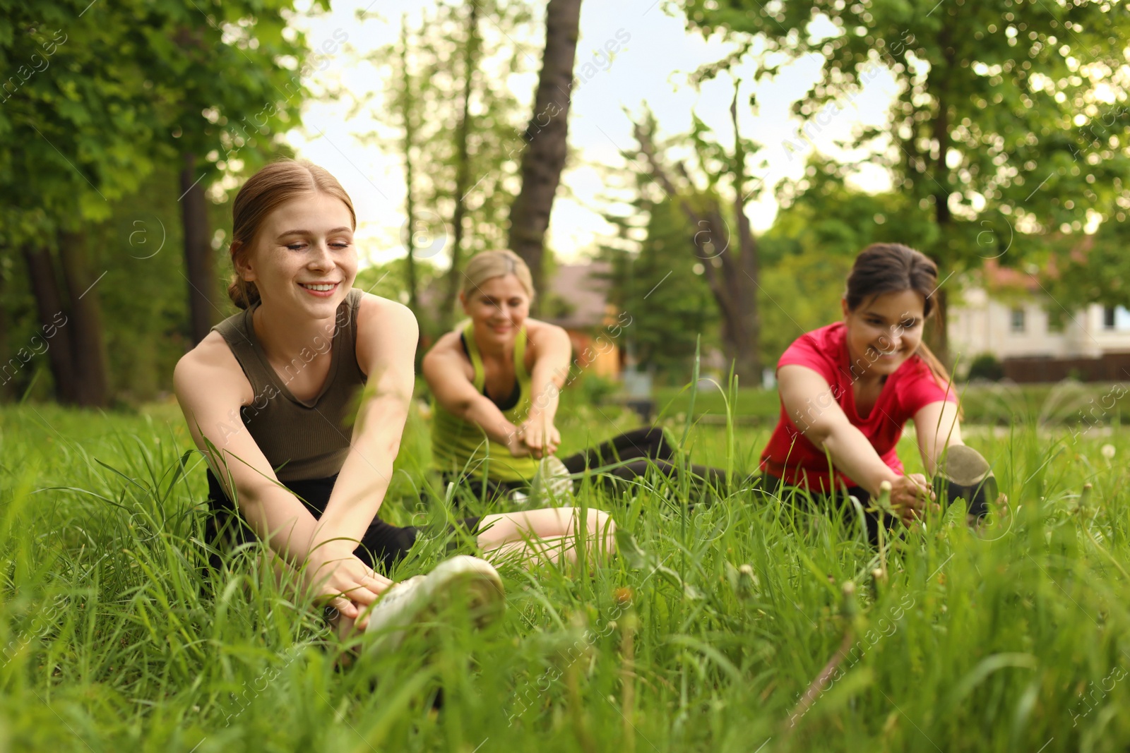 Photo of Women and teenage girl doing morning exercise on green grass in park