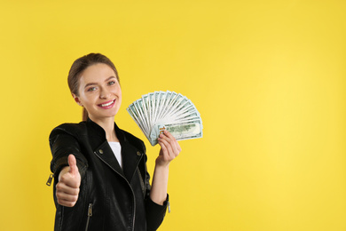 Young woman with money on yellow background. Space for text