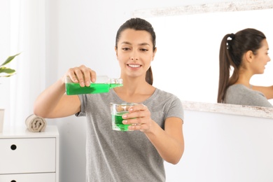 Photo of Young woman with mouthwash in bathroom. Teeth and oral care