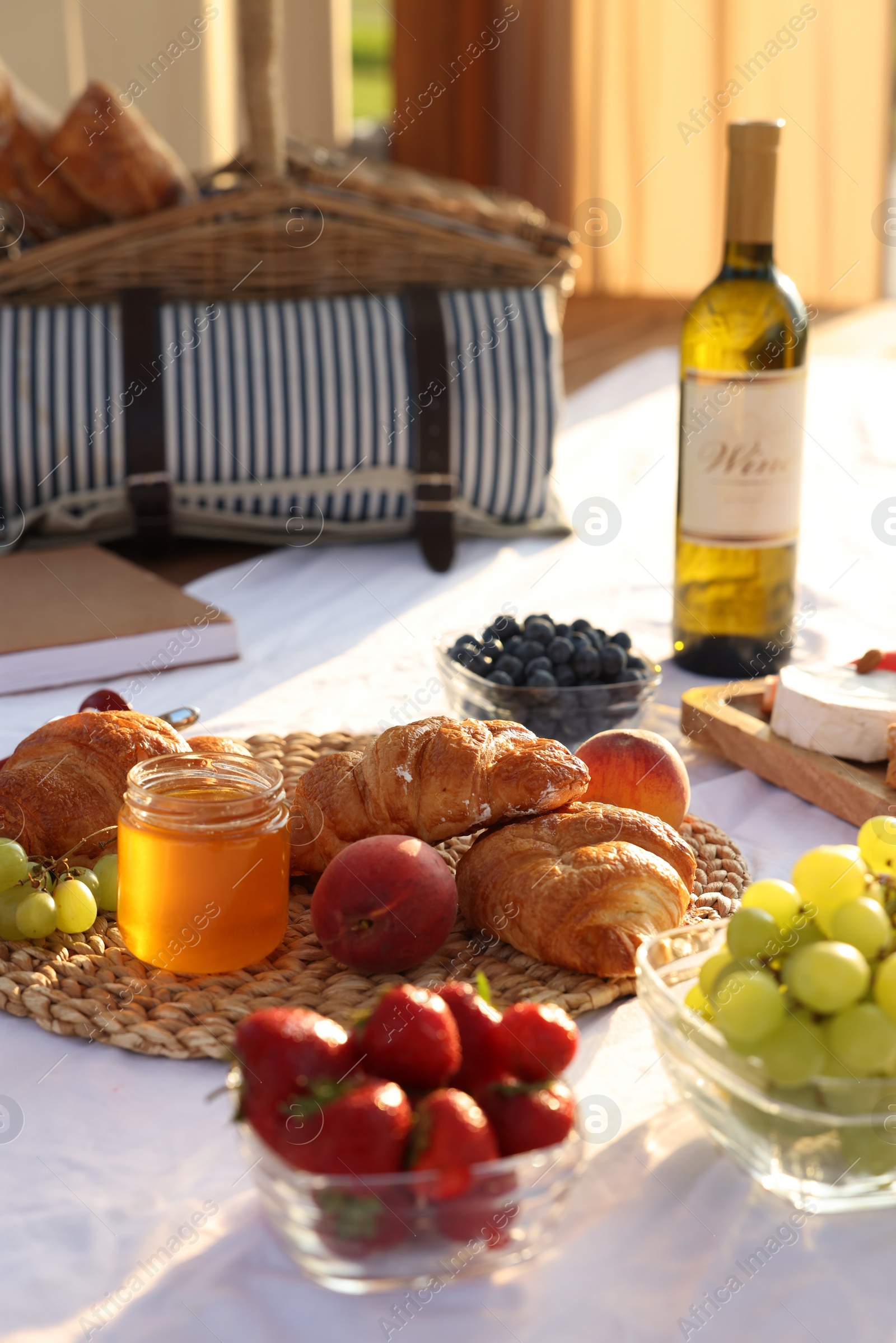 Photo of Romantic date. Delicious snacks for picnic on white blanket outdoors