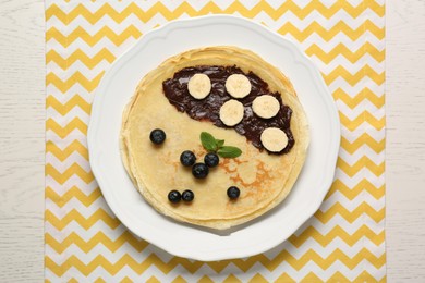 Photo of Stack of delicious crepes with fresh berries, chocolate and banana on white wooden table, top view