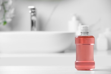 Photo of Bottle of mouthwash on white countertop in bathroom, space for text