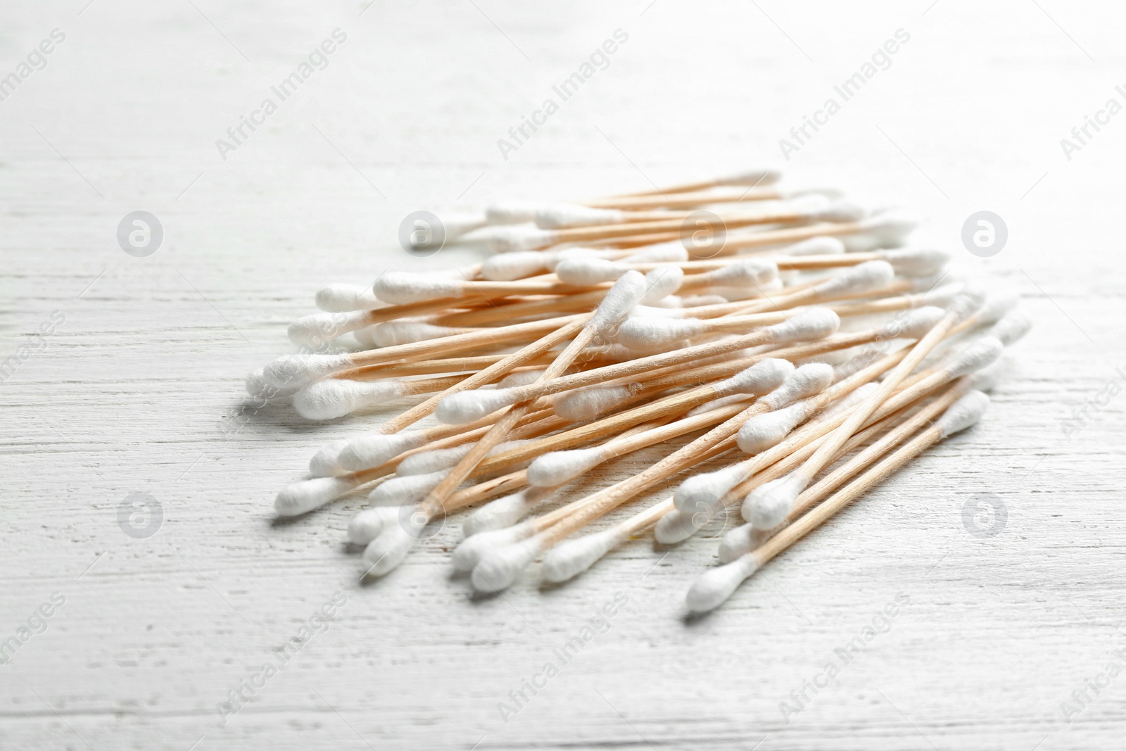 Photo of Pile of cotton swabs on white wooden background