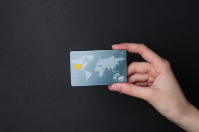 Photo of Woman holding credit card on black background, closeup