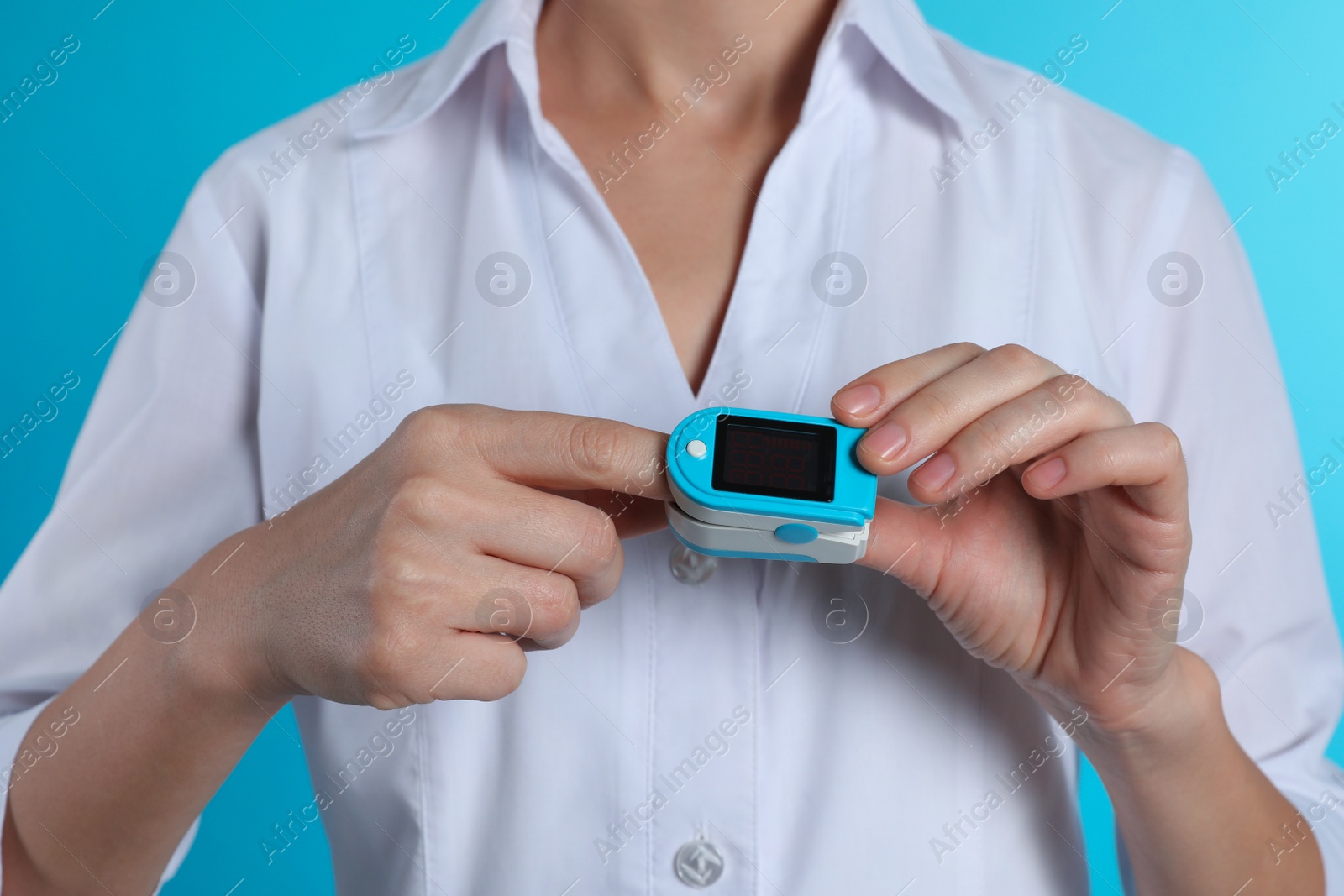 Photo of Female doctor holding pulsimeter on color background, closeup. Medical object