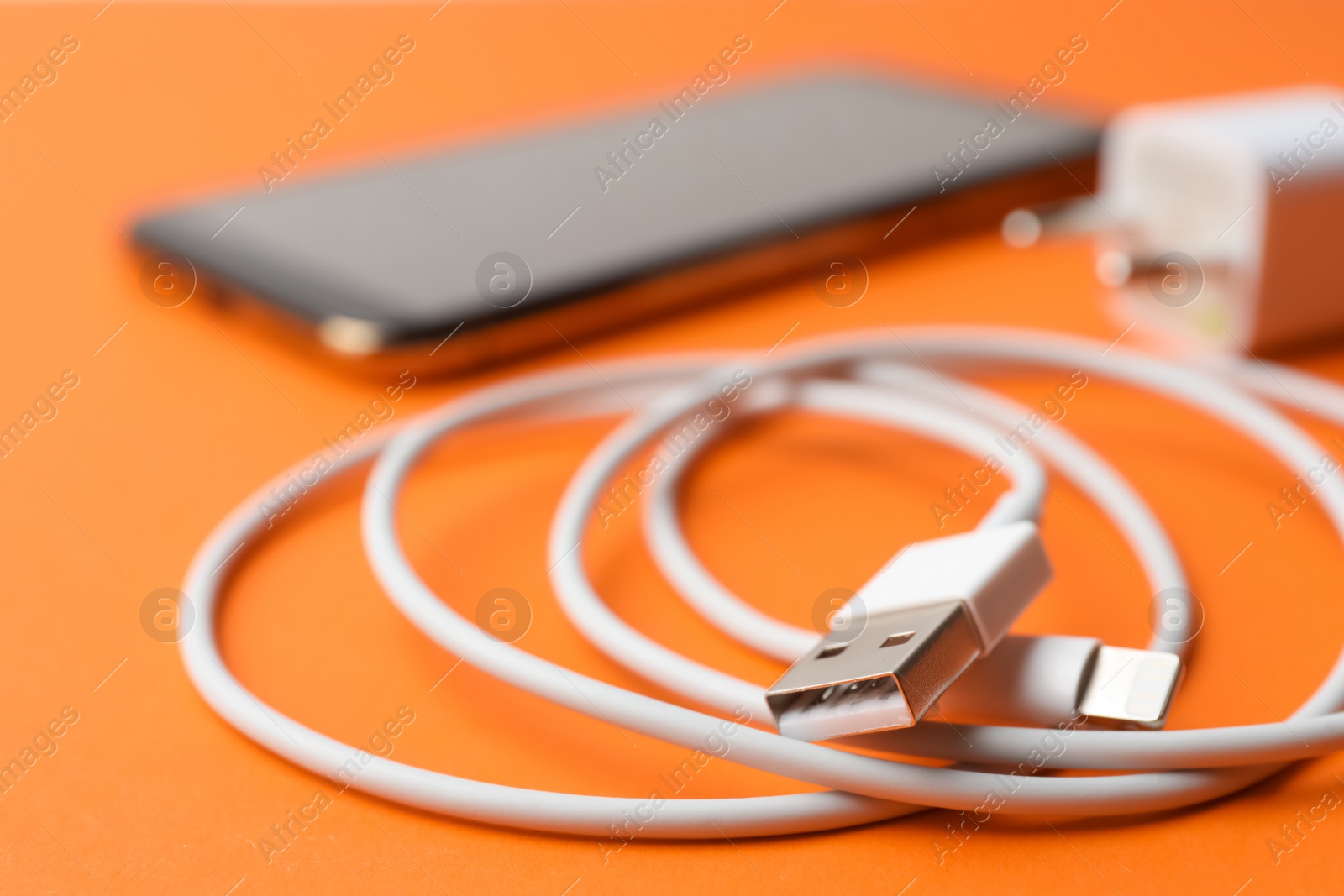 Photo of USB charge cable on orange background, closeup. Modern technology