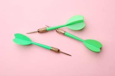 Photo of Green dart arrows on color background, flat lay