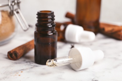 Photo of Bottle and pipette with cinnamon essential oil on table