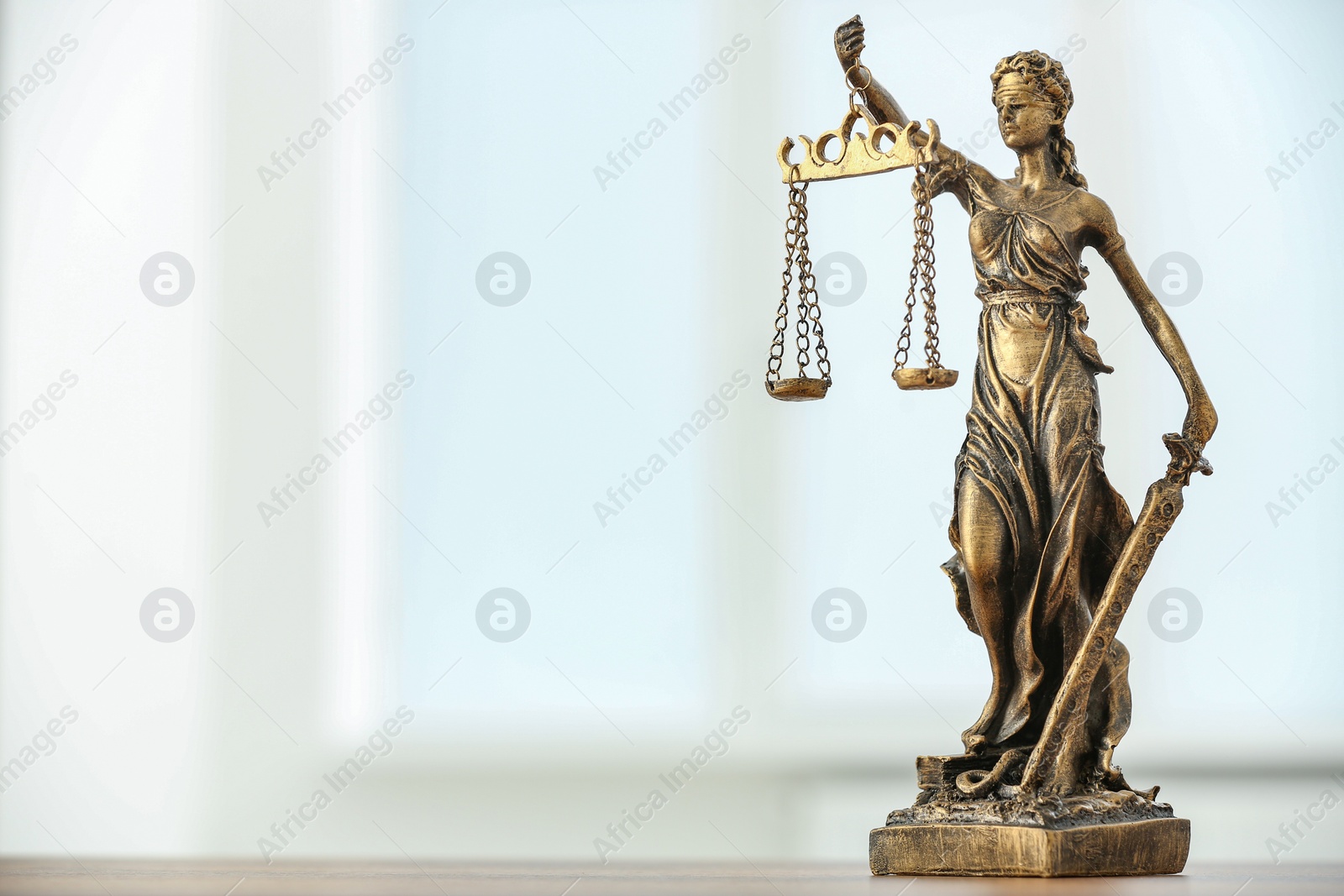 Photo of Figure of Lady Justice and gavel on table against light background, space for text. Symbol of fair treatment under law