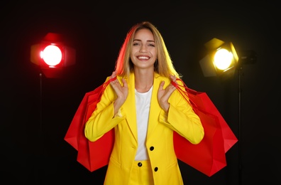 Photo of Happy young woman with shopping bags on dark background. Black Friday Sale