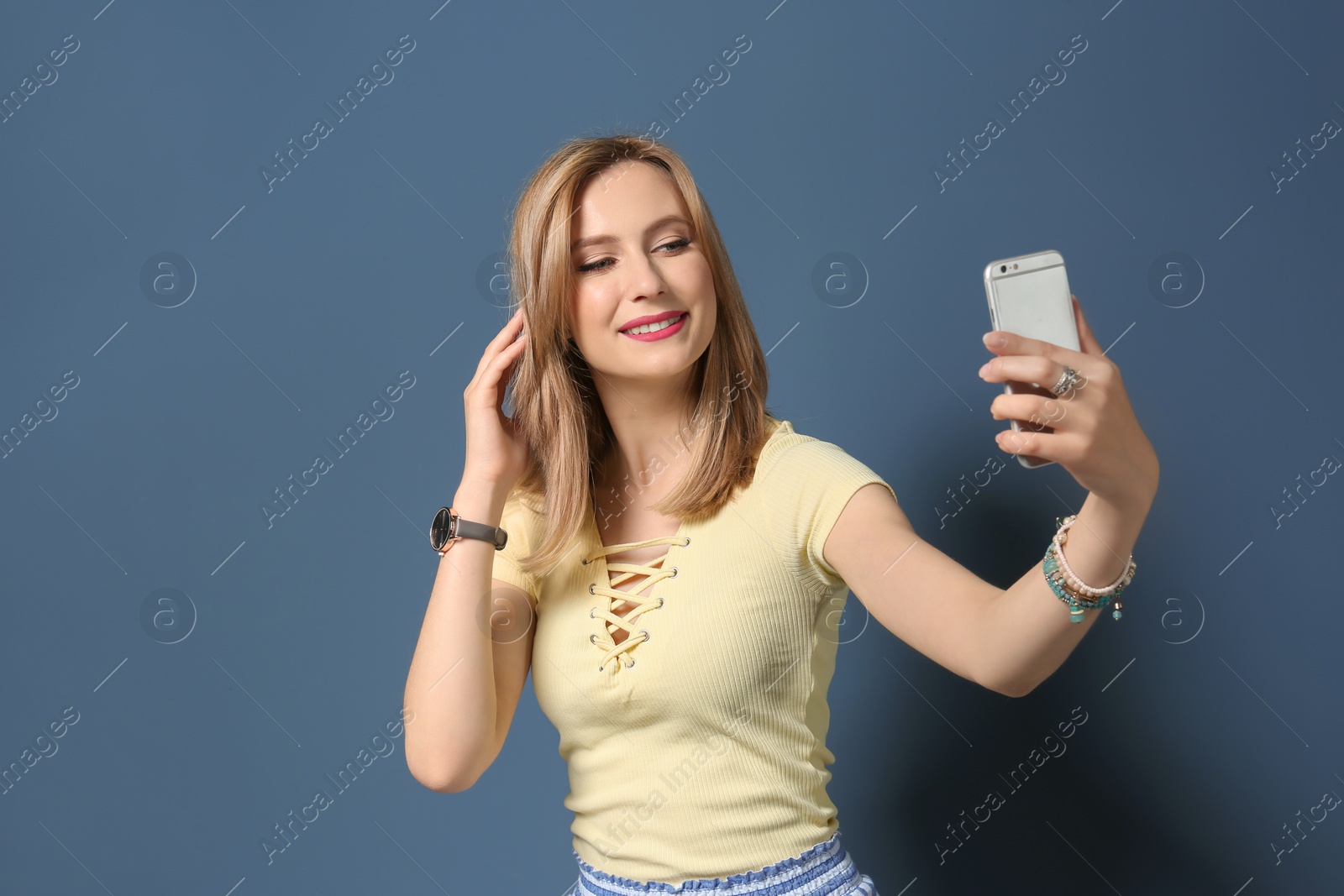 Photo of Attractive young woman taking selfie on color background