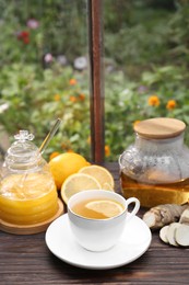 Cup of delicious tea with lemon and honey on wooden table