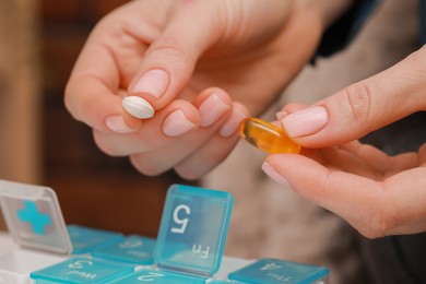 Photo of Woman taking pills from plastic box indoors, closeup