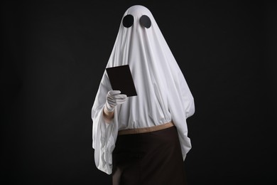 Photo of Creepy ghost. Waiter in white sheet and apron with receipt on black background