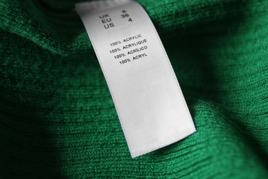 Photo of Clothing label with material content on green shirt, closeup view