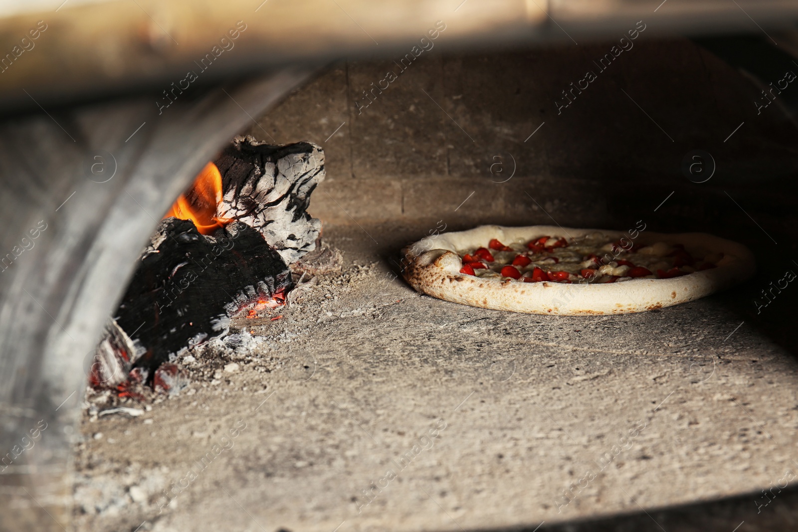 Photo of Oven with burning firewood and tasty pizza in restaurant kitchen