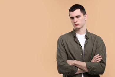 Portrait of sad man on beige background, space for text