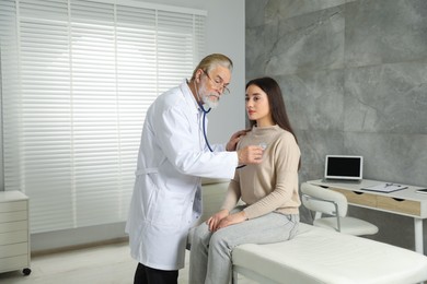 Senior doctor examining patient with stethoscope in clinic