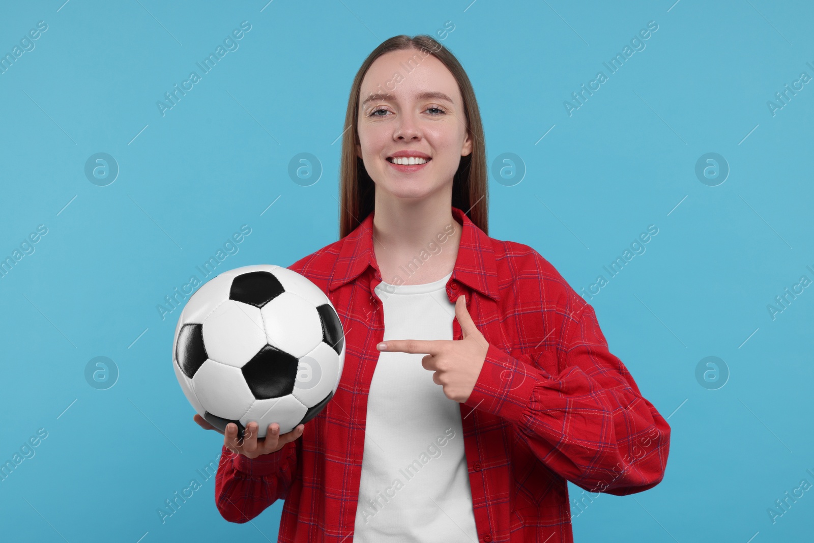 Photo of Happy sports fan with ball on light blue background