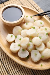 Photo of Raw scallops with green onion and soy sauce on dark table, above view