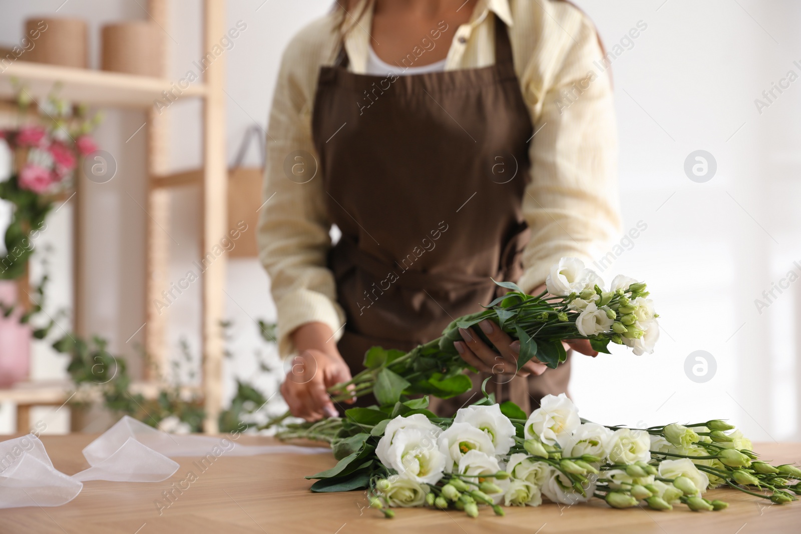 Photo of Florist making beautiful bouquet at table in workshop, closeup