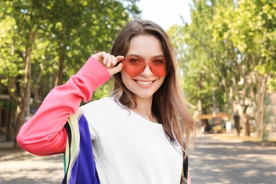Photo of Portrait of happy young woman with heart shaped glasses in spring park. Space for text