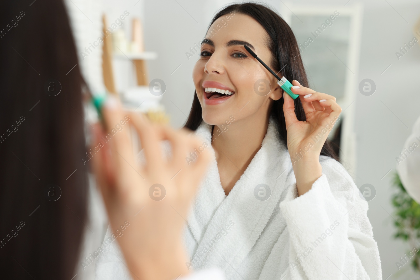 Photo of Beautiful young woman applying mascara in bathroom