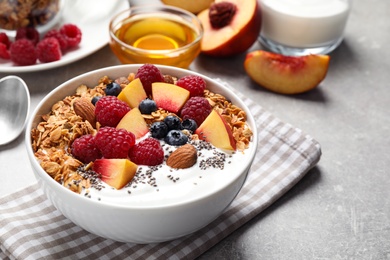 Photo of Tasty homemade granola with yogurt served on grey table. Healthy breakfast