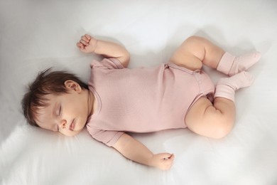 Photo of Cute little baby sleeping on cosy bed, top view