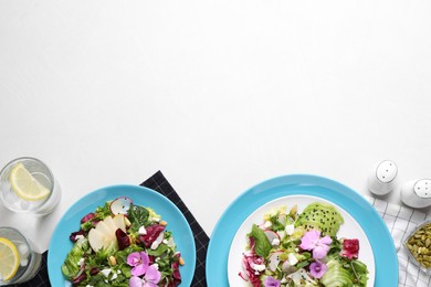 Photo of Fresh spring salads with flowers served on white table, flat lay. Space for text