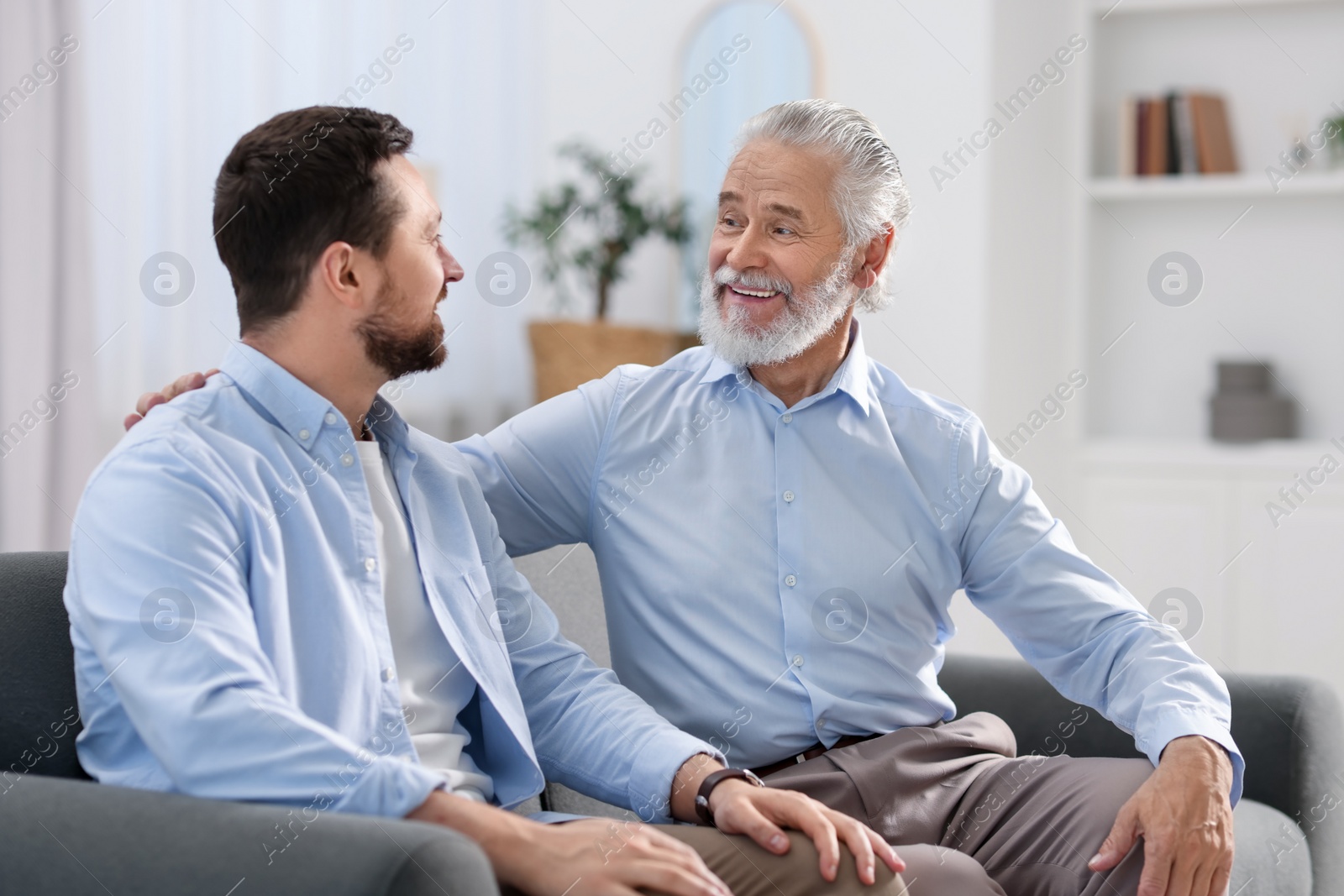 Photo of Happy son and his dad on sofa at home