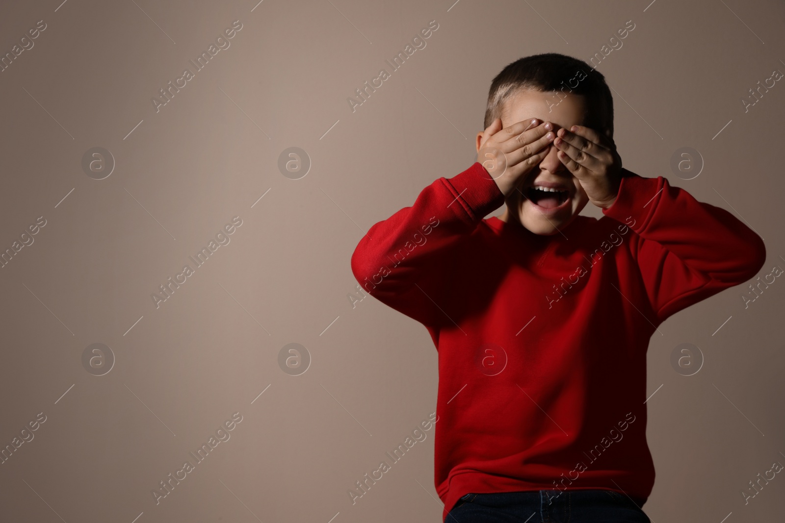 Photo of Scared little boy on beige background, space for text. Domestic violence concept