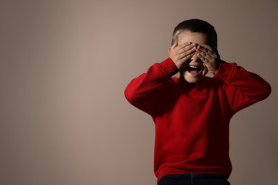 Photo of Scared little boy on beige background, space for text. Domestic violence concept