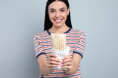 Photo of Happy young woman with delicious shawarma on grey background