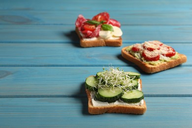 Tasty toasts with different toppings on light blue wooden table. Space for text