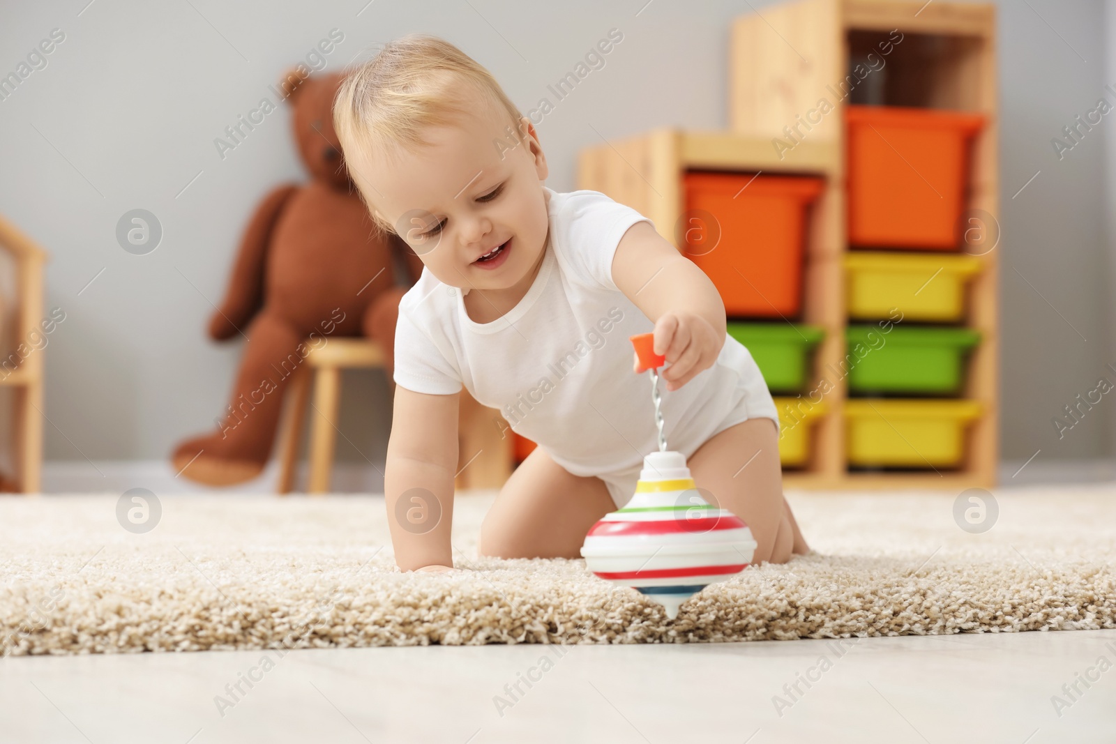 Photo of Children toys. Cute little boy playing with spinning top on rug at home