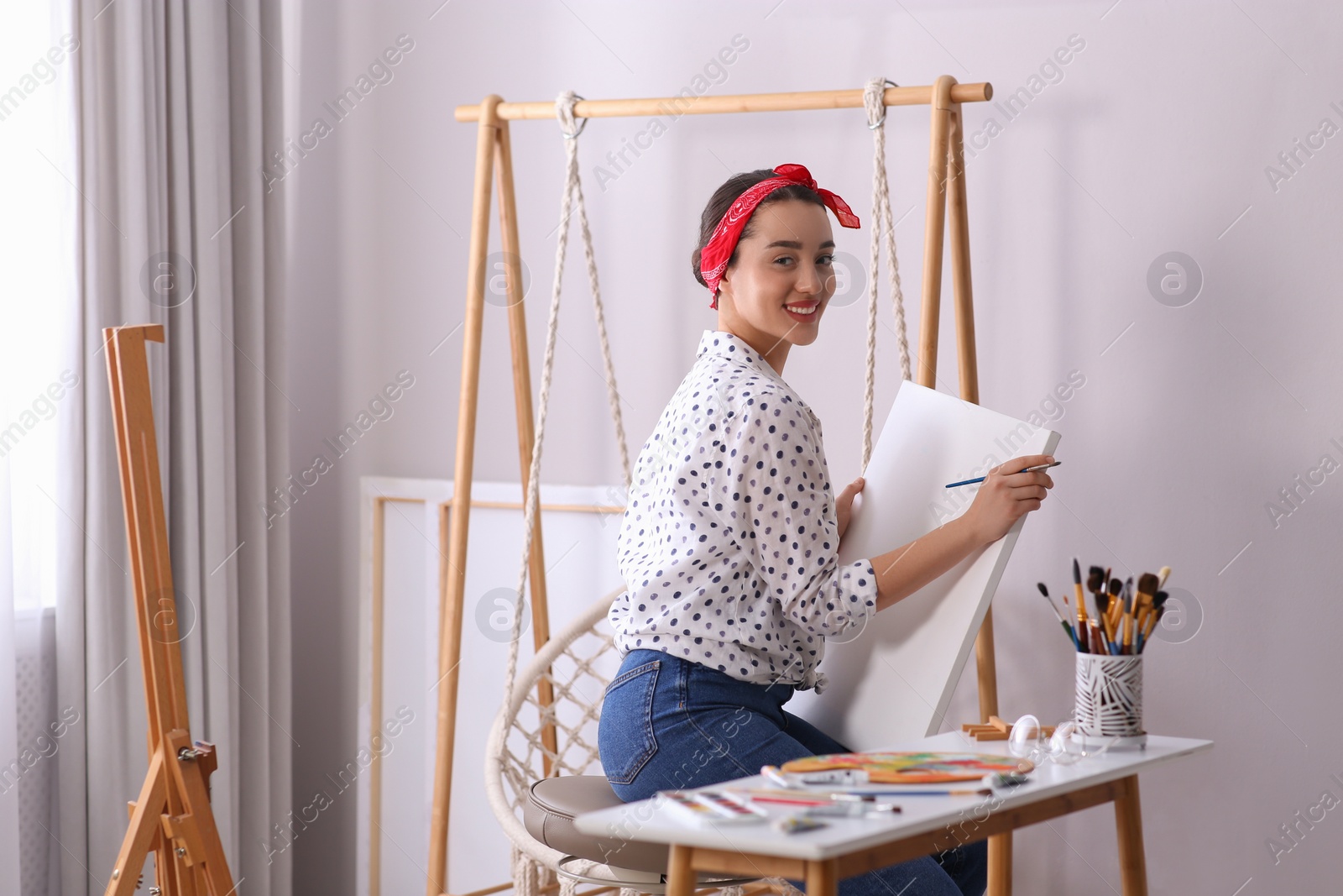 Photo of Happy woman artist drawing picture on canvas in studio