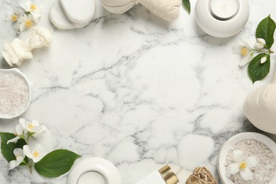 Photo of Jasmine flowers and set of spa essentials on white marble table, flat lay. Space for text