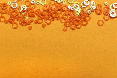 Shiny bright glitter on light orange background, flat lay. Space for text